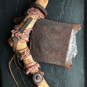 May include: A rustic axe with a wooden handle wrapped in twine and leather. The axe head is rusty and has a chipped edge.