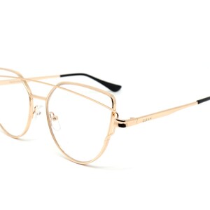 May include: Gold-tone metal cat-eye glasses with a double bridge design. The glasses have clear lenses and the brand name "GLEAM" is printed on the right temple.