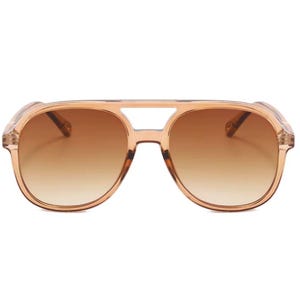 May include: Clear aviator sunglasses with brown gradient lenses. The frames are a light peach color. The sunglasses have a double bridge and a classic aviator shape.