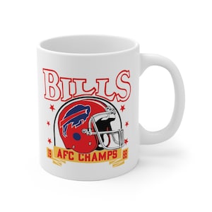 May include: White ceramic coffee mug with a red, white, and blue Buffalo Bills logo and the text "Bills" in red and "AFC Champs 98" in gold.