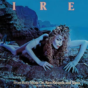 May include: A woman with long blonde hair wearing a crown lies on a rocky shore. The water is blue and the sky is a deep blue. The text "SIREN" is written in pink letters at the top of the image. The text "From Roxy Music On Atco Records and Tapes" is written in white letters at the bottom of the image.