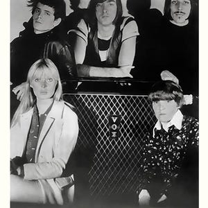 May include: A monochrome photograph of The Velvet Underground and Nico. The band is positioned in front of a Vox amplifier. The members are wearing dark attire. The image includes the text "THE VELVET UNDERGROUND AND NICO" at the bottom.