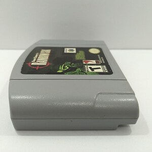 May include: A gray Nintendo 64 video game cartridge. The label features the game title "Turok 2: Seeds of Evil" with a green and black graphic. The cartridge has a "T" for Teen rating.