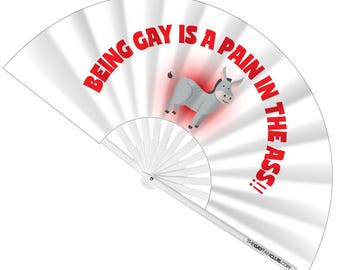 May include: White hand fan with a cartoon donkey and the text "BEING GAY IS A PAIN IN THE ASS!!" in red. The fan has a white handle and the website address "THEGAYFANCLUB.COM" printed on the bottom.