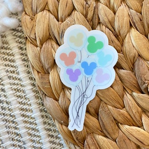 May include: A die-cut sticker featuring a cluster of seven translucent balloons, each containing a solid pastel-colored Mickey Mouse head silhouette in yellow, green, orange, blue, purple, and light pink, connected by thin black string illustrations.