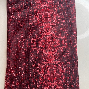 Puede incluir: Tela roja con estampado de piel de serpiente y acabado brillante.