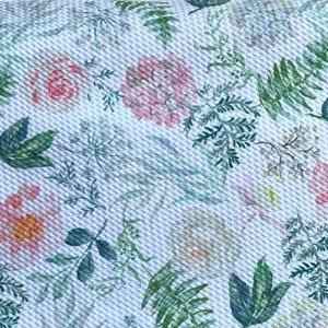 May include: White fabric with a repeating pattern of pink and green floral designs. The fabric features a variety of flowers, leaves, and ferns.