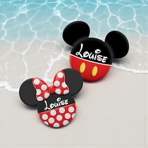 May include: Two Mickey and Minnie Mouse-themed accessories. One is red, black, and yellow with the name "Louise" in white. The other is black, red, and white with a polka dot bow and the name "Louise".