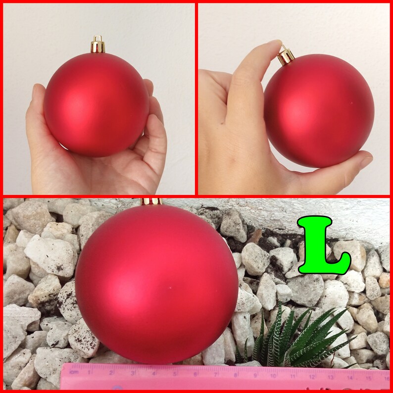 May include: A large, matte red Christmas ornament with a gold cap. The ornament is held in a hand in two of the images. The third image shows the ornament on a bed of rocks with a small succulent plant and a ruler.