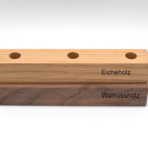 May include: Two wooden blocks stacked on top of each other. The top block is light brown and says "Eicheholz". The bottom block is dark brown and says "Walnuss holz".