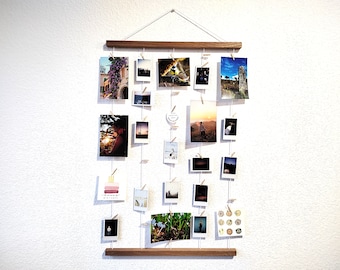 Op de afbeelding: Een houten fotodisplay met touw en wasknijpers die aan een houten balk hangen. De display is gevuld met verschillende foto's en ansichtkaarten.