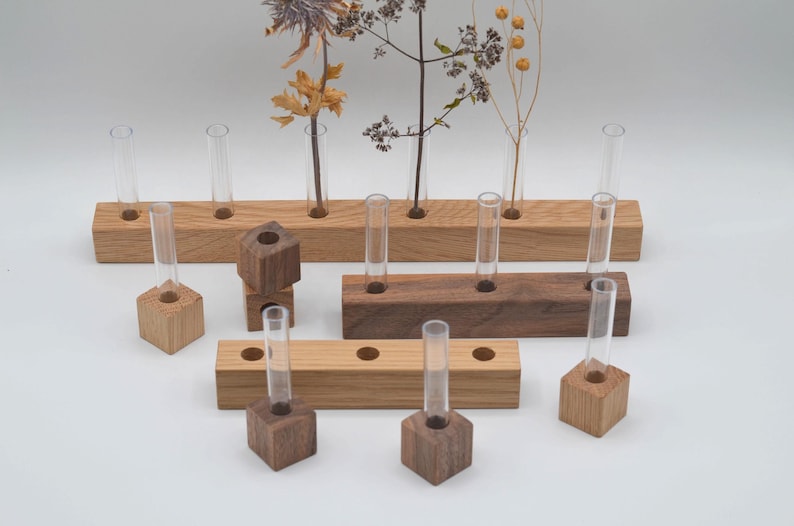 May include: A set of wooden test tube holders with clear glass test tubes. The holders are made of both light and dark wood and come in different sizes. The set includes both single and multiple test tube holders.