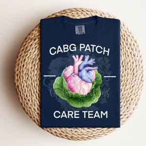 Peut inclure: Un t-shirt bleu marine avec un graphique blanc d'un cœur dans un chou avec le texte "CABG PATCH CARE TEAM".