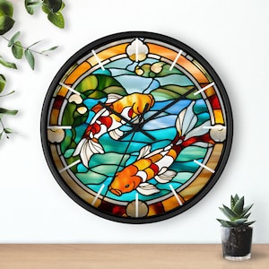 May include: A round wall clock with a stained glass design featuring two orange and white koi fish swimming in a blue and green pond. The clock has black hands and a black frame.