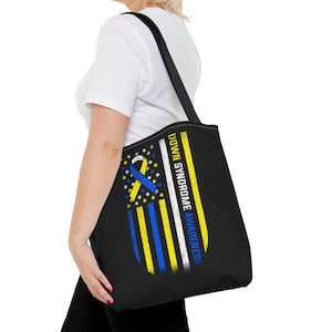 May include: Black tote bag with a blue and yellow ribbon design and the text "Down Syndrome Awareness" on a white background.