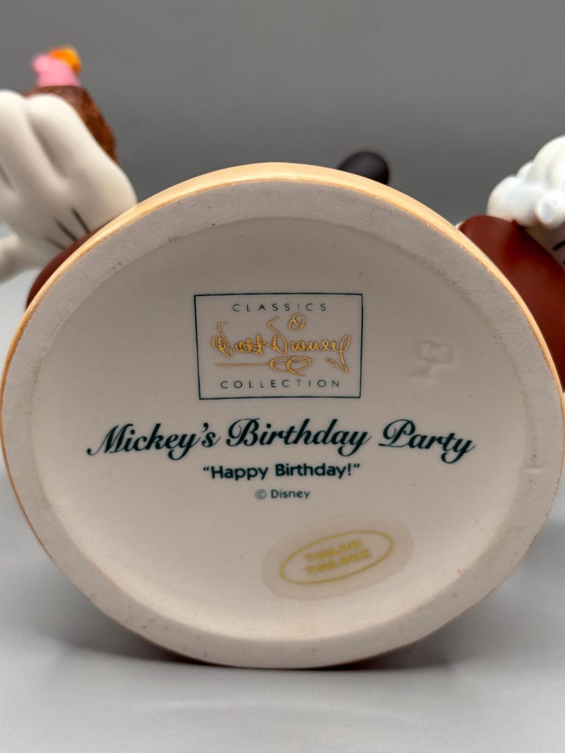 Pu&ograve; includere: Un oggetto da collezione Disney in ceramica, con la festa di compleanno di Topolino. La base &egrave; color crema con la scritta "Mickey's Birthday Party" e "Happy Birthday!". &Egrave; visibile anche il logo Disney Classics Collection.