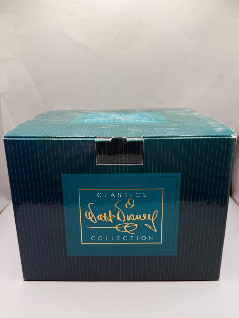 Pu&ograve; includere: Una scatola verde acqua e blu navy a righe verticali. La scatola presenta un'etichetta con cornice dorata con le parole "CLASSICS" e "Walt Disney COLLECTION" in lettere dorate. La scatola &egrave; chiusa con una linguetta nera.