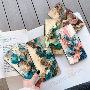 May include: Six different phone cases featuring abstract marble designs in shades of blue, green, gold, and white. The cases have a textured, painted look.