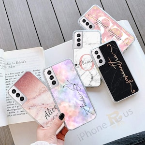 May include: Five different phone cases with marble and glitter designs. Each case has a different name written on it: Olivia, Samantha, Alice, Amelia, and Olympus. The cases are clear and show the phone through the design.