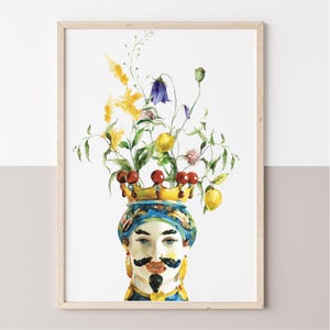 May include: Watercolor print of a decorative vase with a face, adorned with a golden crown and filled with flowers, lemons, and cherries. The vase has a blue and yellow turban and a black mustache. The artwork is framed in a light wood frame.