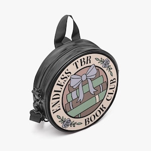 May include: Black round crossbody bag with a top handle and a detachable shoulder strap. The bag features a circular design with the text "ENDLESS TBR BOOK CLUB" around a graphic of books and a bow.