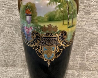 May include: A black and gold Japanese porcelain vase with a hand-painted landscape scene and gold accents. The vase has two handles and a delicate floral design.