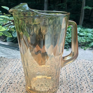 Puede incluir: Una jarra de vidrio transparente con un patrón texturizado en forma de panal. La jarra tiene un asa y una boca ancha.