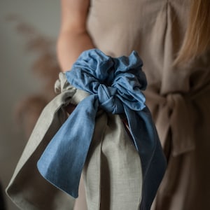 Peut inclure: Un chouchou en tissu bleu et beige noué en forme de nœud. Le chouchou est fait d'un tissu doux et texturé.