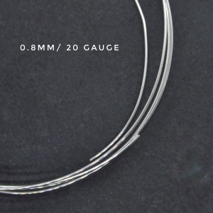 May include: Close-up of three strands of silver wire, each measuring 0.8mm or 20 gauge in diameter. The wire is coiled and appears to be on a dark gray surface.