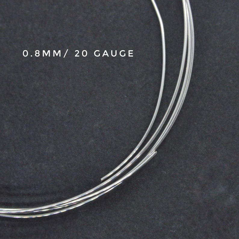 May include: Close-up of three strands of silver wire, each measuring 0.8mm or 20 gauge in diameter. The wire is coiled and appears to be on a dark gray surface.