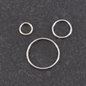 Op de afbeelding: Drie zilveren springringen in verschillende maten. De ringen zijn glad en glanzend.