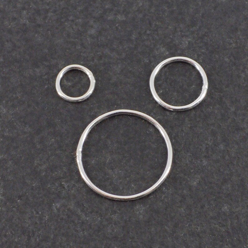 Op de afbeelding: Drie zilveren springringen in verschillende maten. De ringen zijn glad en glanzend.