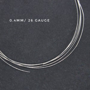 May include: Close-up of silver wire, 0.4mm in diameter, or 26 gauge. The wire is coiled on a dark gray surface.