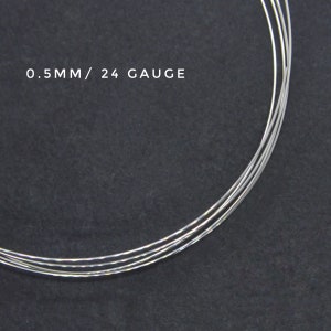 May include: Close-up of silver wire, 0.5mm in diameter, or 24 gauge. The wire is coiled and appears to be for jewelry making.