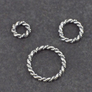 Op de afbeelding: Drie zilveren springringen met een gedraaid touwontwerp. De ringen zijn in verschillende maten.