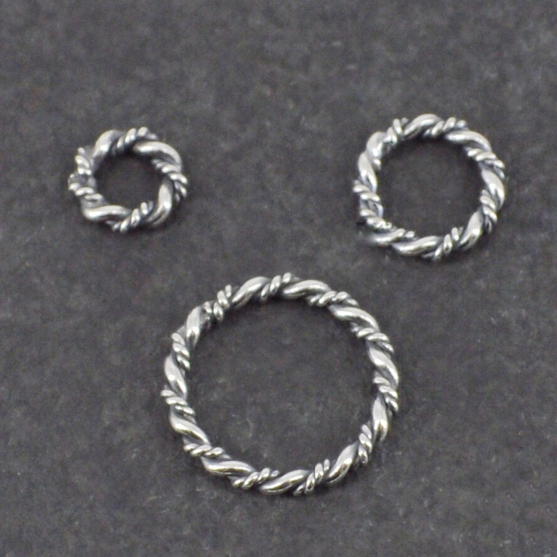 Op de afbeelding: Drie zilveren springringen met een gedraaid touwontwerp. De ringen zijn in verschillende maten.