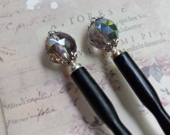 May include: Two black wooden hair sticks with iridescent crystal beads on the top. The beads are set in silver tone metal.