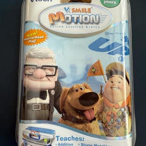 May include: VTech V.Smile Motion Active Learning System for ages 4-6, featuring Disney Pixar's "Up" characters. The package includes a game console and controller. The game teaches addition, shape matching, patterns, and colors.