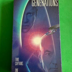 May include: A VHS tape case for the film Star Trek: Generations. The cover features a blue and red Starfleet insignia with the faces of Captain Kirk and Captain Picard. The text on the case reads "Two Captains. One Destiny."