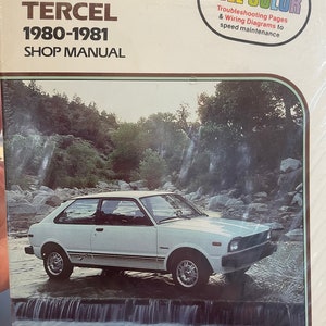 May include: A Clymer Toyota Tercel Shop Manual for the years 1980-1981. The cover features a white Toyota Tercel driving through a stream with a waterfall in the background. The manual includes over 35 full-color troubleshooting pages and wiring diagrams to speed maintenance.