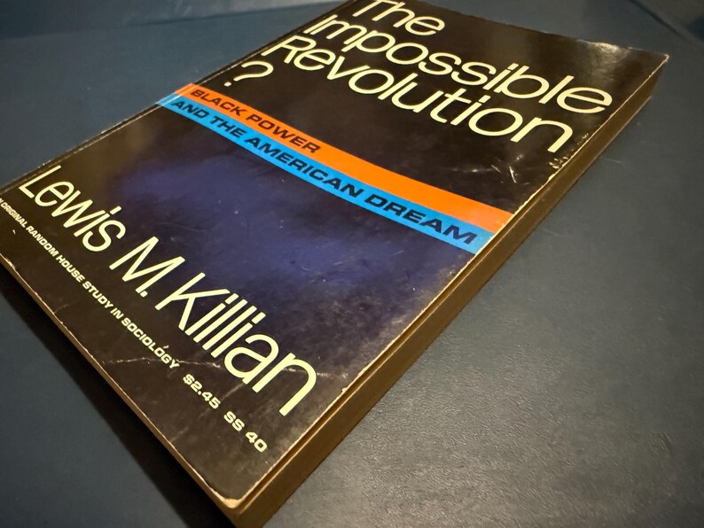Op de afbeelding: Een hardcover boek met de titel "The Impossible Revolution?" van Lewis M. Killian. De omslag is donker met witte tekst en een blauwe, oranje en zwarte streep. De ondertitel is "Black Power and the American Dream."