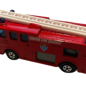 May include: Red toy fire truck with a white ladder on top. The truck has "LONDON FIRE SERVICE" printed on the side with a crest.