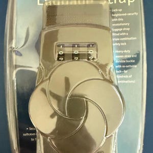 May include: A Samsonite triple-combination luggage strap in a clear plastic package. The strap has a combination lock with three dials and a woven strap. The packaging includes text describing the strap's features.