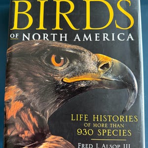 May include: A hardcover book titled "BIRDS of NORTH AMERICA" by Smithsonian. The cover features a close-up of a bird's head with brown, orange, and black feathers. The book includes "LIFE HISTORIES of MORE THAN 930 SPECIES".