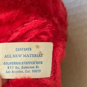 May include: A white tag with blue text that reads "CONTENTS ALL NEW MATERIAL CALIFORNIA STUFFED TOYS 611 So. Anderson St. Los Angeles, Cal. 90023".