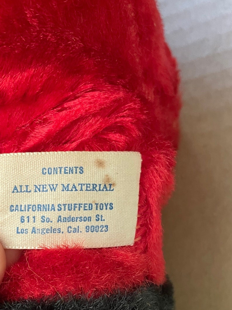 May include: A white tag with blue text that reads "CONTENTS ALL NEW MATERIAL CALIFORNIA STUFFED TOYS 611 So. Anderson St. Los Angeles, Cal. 90023".