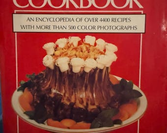 May include: The Culinary Arts Institute Cookbook, a red hardcover book with a white title and subtitle. The book features a photo of a roasted rack of lamb with a white sauce and garnished with green herbs. The book includes over 4400 recipes and more than 500 color photographs.