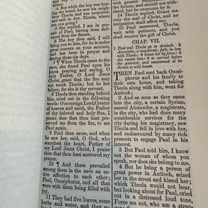 May include: An open book displaying text from the Bible, with the title "PAUL AND THECLA" at the top. The text is printed in black ink on aged, yellowed paper, with a visible binding.