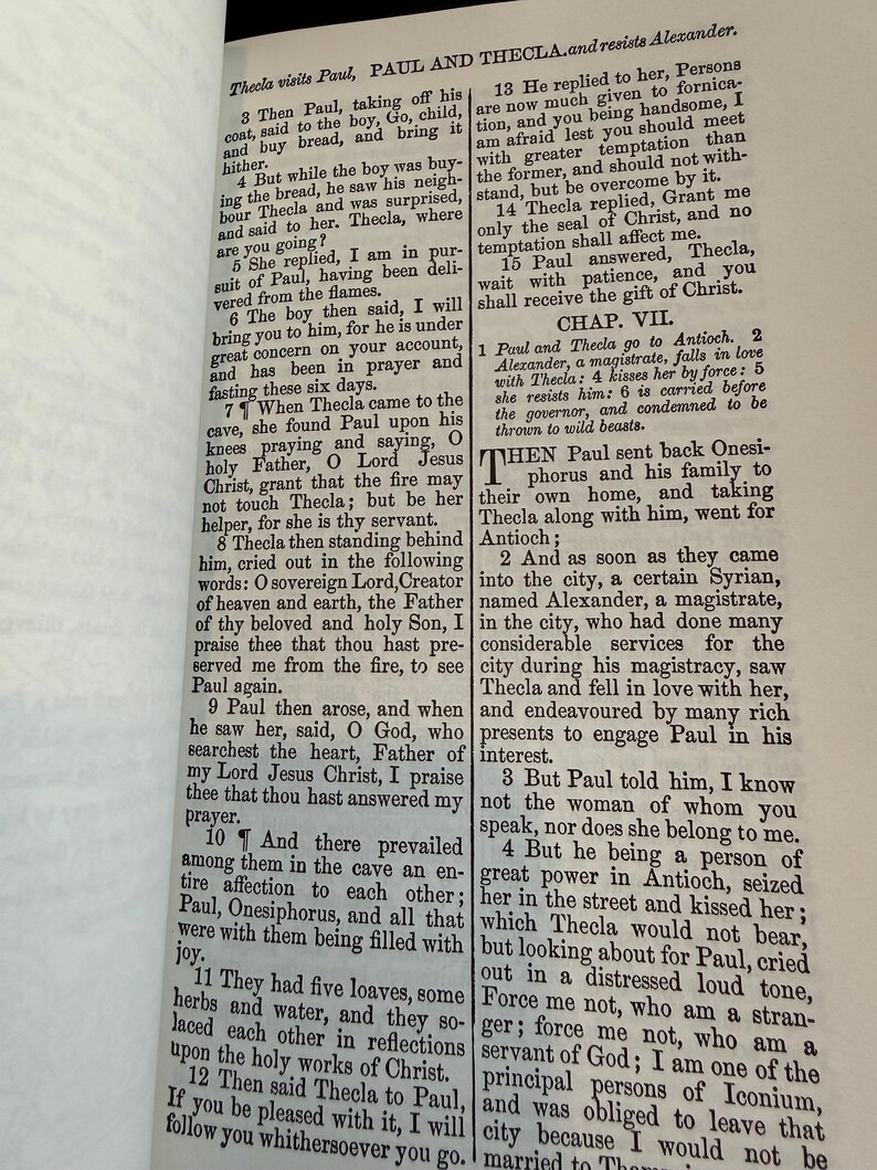 May include: An open book displaying text from the Bible, with the title "PAUL AND THECLA" at the top. The text is printed in black ink on aged, yellowed paper, with a visible binding.