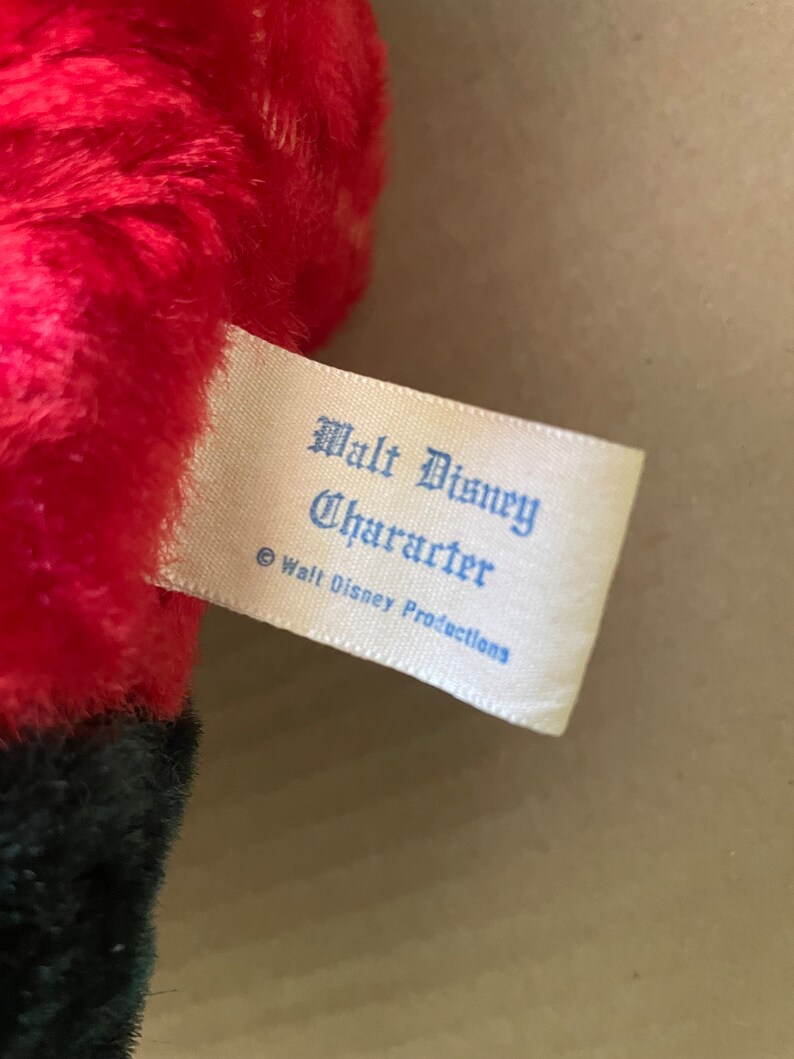 May include: A white tag with blue text that reads "Walt Disney Character &copy; Walt Disney Productions".